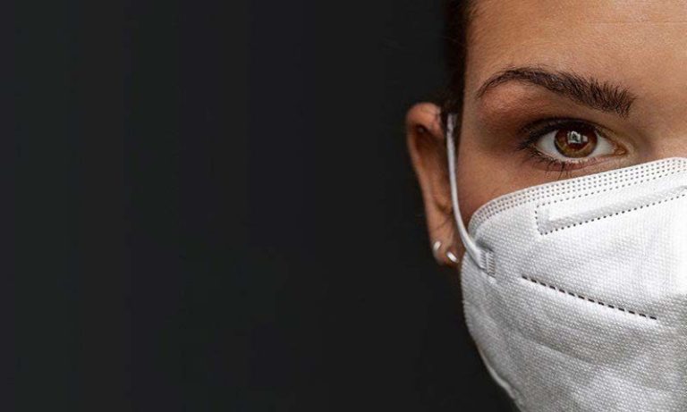 Masked man receives vaccination on arm by a female medical professional